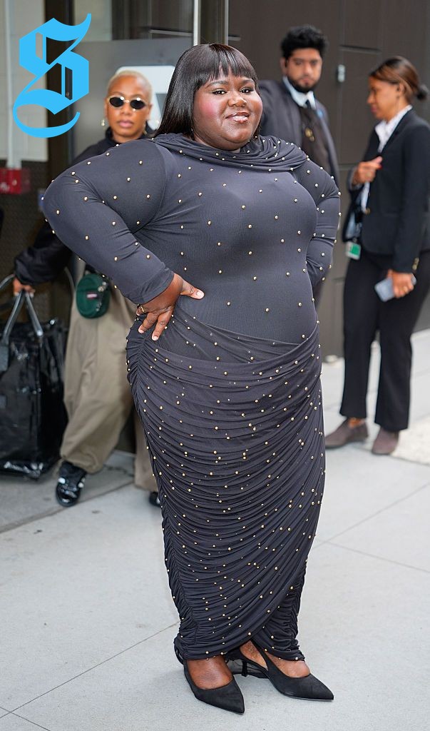Gabourey in a fitted charcoal maxi dress with gold embellishments.