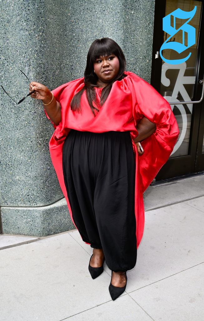 Gabourey wearing balloon pants and a vibrant red top with dramatic sleeves.
